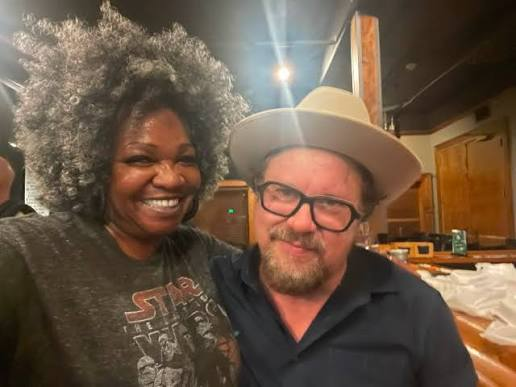 Trina Meade backstage with a collaborator in a hat, both laughing